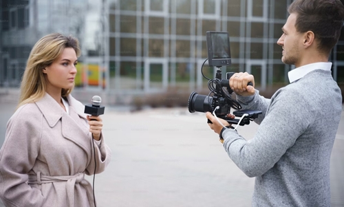 Independent journalist conducting an interview in a public setting, capturing real-time stories from the ground.